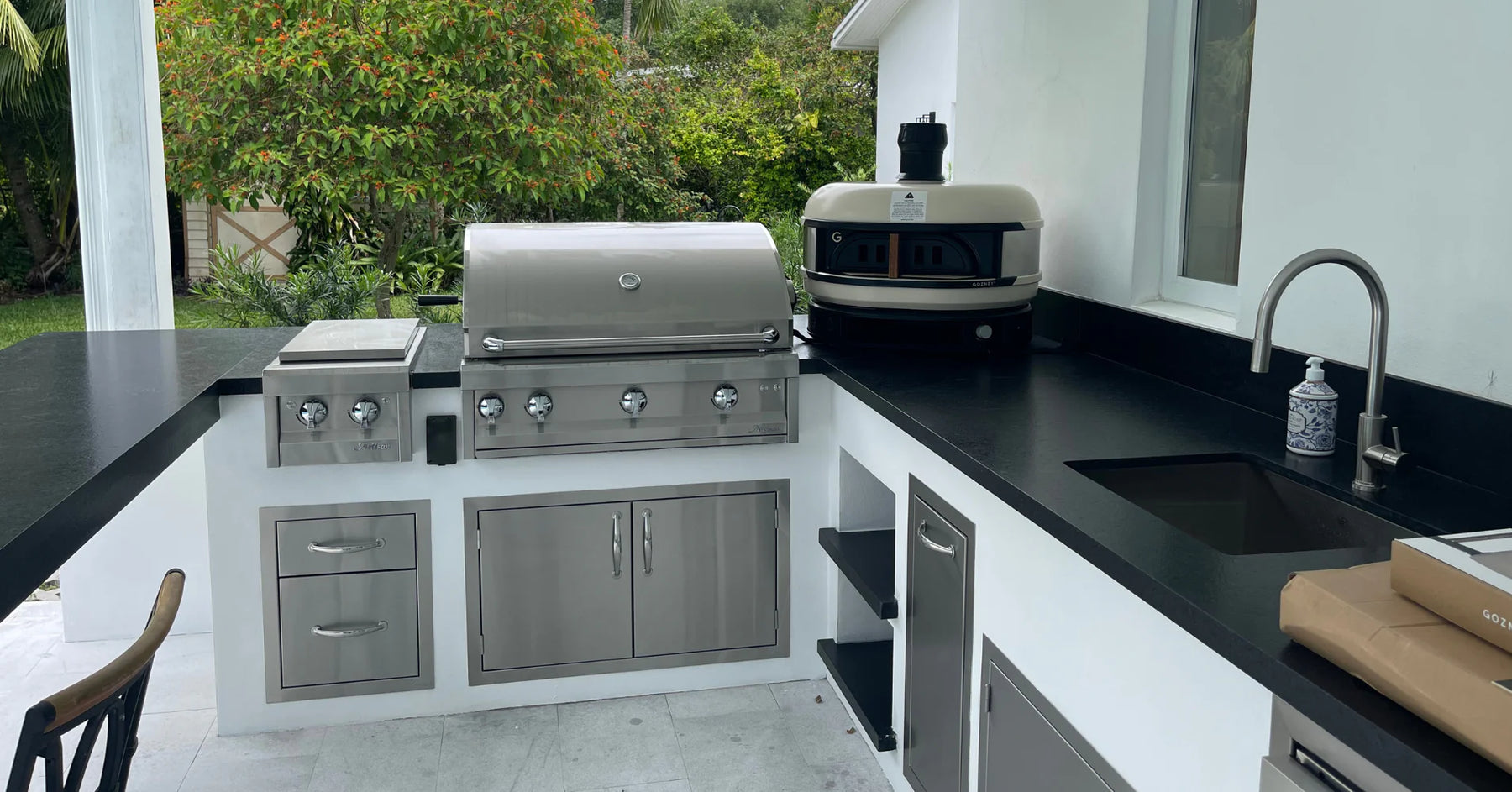 Modern outdoor kitchen design 2025 with stainless steel grill and bar island.